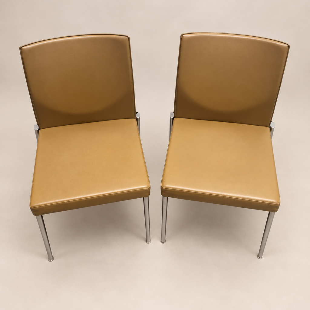 Two matching caramel-tan KFF upholstered armless high-back chairs with slim chrome-finish legs, actual-item hero