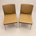 Two matching caramel-tan KFF upholstered armless high-back chairs with slim chrome-finish legs, actual-item hero