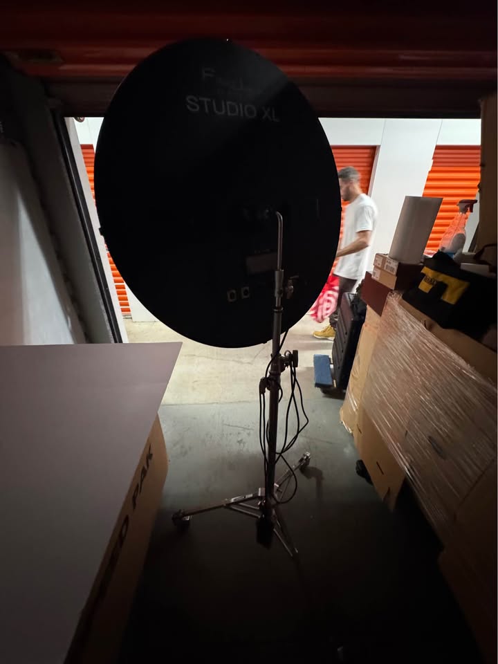 Actual full rear view of the FlapJack Studio XL LED light and rolling stand; surrounding storage area and bystander visible