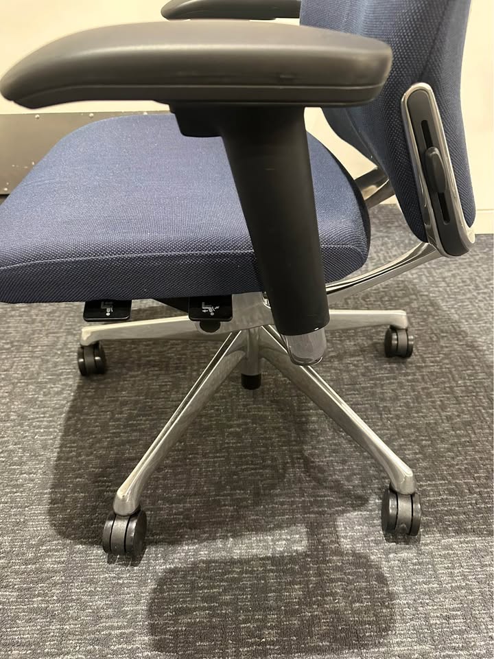 Actual blue upholstered rolling office chair — left side and armrest detail