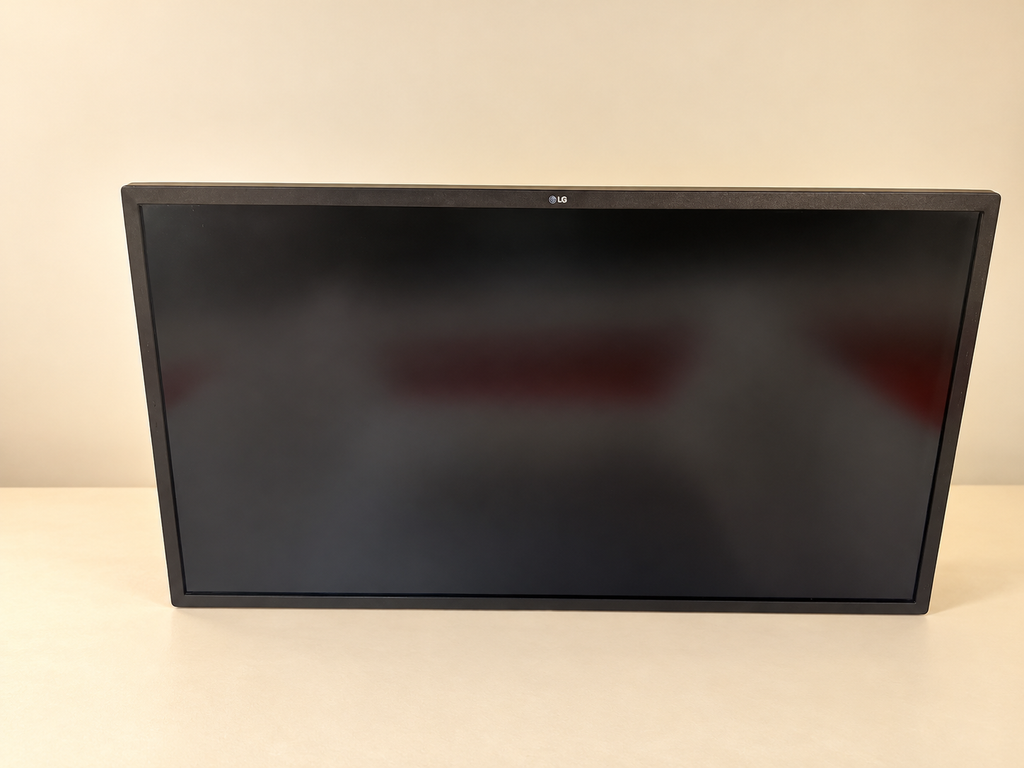 Actual LG monitor alternate front view, screen off; staged cream background, no stand.