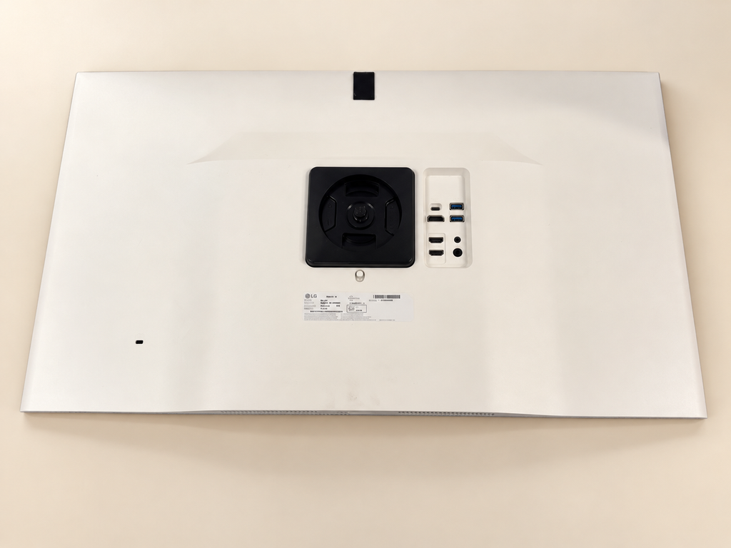 Actual LG monitor rear with visible marks and mounting recess; staged cream background, no stand.