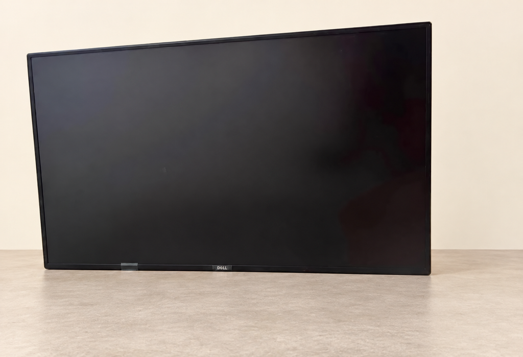 Front view of the exact Dell U4323QE monitor with dark screen and no stand; storage-door background replaced with a cream studio setting.
