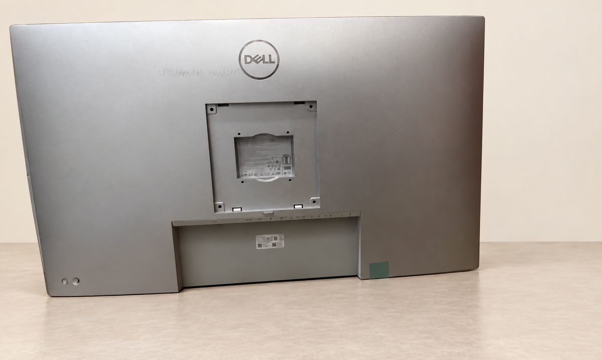 Rear view of the exact Dell U4323QE showing the mounting recess and visible marks; no stand; background staged clean.